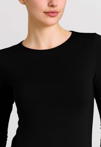 Maglietta nera a maniche lunghe con scollatura rotonda, realizzata in tessuto liscio; presenta un design aderente, senza motivi o accessori visibili.