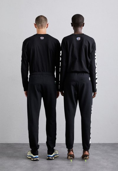 Black long-sleeve shirts and pants, featuring a white logo and text, made of a smooth fabric, with elastic cuffs and waistband.