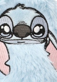Tejido azul esponjoso con detalles faciales bordados en negro y blanco. Presenta ojos grandes y expresivos y orejas interiores rosas.
