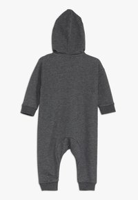 Czarny szary kombinezon z kapturem wykonany z miękkiego materiału. Posiada długie rękawy, ściągacze na nadgarstkach oraz okrągłe wycięcie z tyłu dla swobody ruchów.