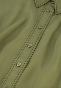 Olijfgroene shirt met een gladde textuur, voorzien van een puntige kraag, zeven knopen aan de voorkant en contrasterende stikdetails.