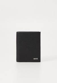 Portefeuille en cuir noir avec une finition texturée, design à rabat, et un logo argenté dans le coin inférieur droit. Forme simple et compacte.