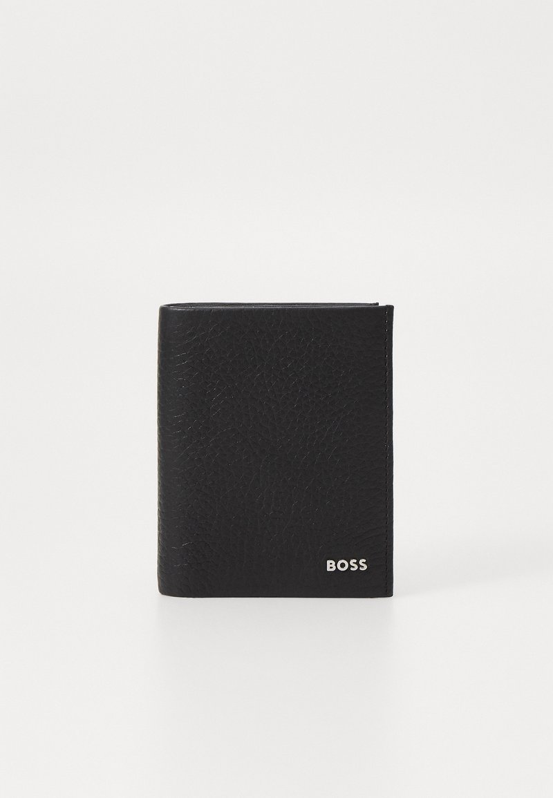 Portefeuille en cuir noir avec une finition texturée, design à rabat, et un logo argenté dans le coin inférieur droit. Forme simple et compacte.