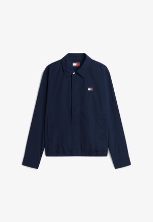 Chaqueta ligera de color azul marino con cuello, mangas largas, bolsillos frontales, dobladillo elástico y pequeño logo de Tommy Jeans en el pecho izquierdo.