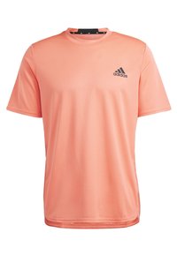 Camiseta deportiva de Adidas en color naranja claro, con mangas cortas, cuello redondo, tejido texturizado y un pequeño logotipo negro en la parte superior izquierda del pecho.