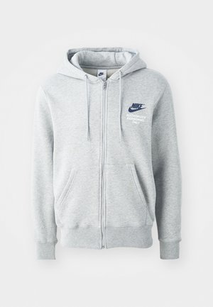 Szara bluza z kapturem zapinana na zamek, wykonana z miękkiego materiału. Ma kieszenie kangurze, sznurki w kapturze oraz niebieskie logo Nike z napisem "Tylko uprawniony personel".