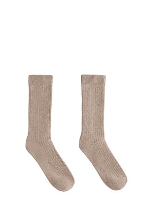 Beiga ribbade strumpor av mjukt material, med medellång längd till vaden och ett strukturerat mönster samt förstärkt tåparti.