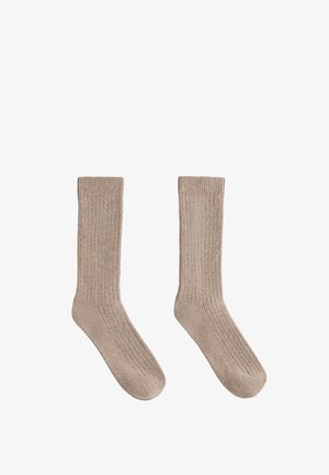 Beige ribbed socks made from soft material, featuring a mid-calf length with a textured pattern and reinforced toe area.