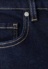 Mørkeblå denim jeanslomme med beige syninger, metalnitte og detalje med bæltestrop.