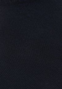 Knæhøje marineblå sokker lavet af blødt, tekstureret stof med et ribbet mønster og glat finish, med en elastisk åbning for en sikker pasform.