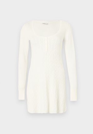 Λευκό πλεκτό φόρεμα με μακριά μανίκια, στρογγυλή λαιμόκοψη και σχέδιο πλεξούδας. Διαθέτει κουμπιά στο εμπρόσθιο μέρος και ριμπ μανσέτες.