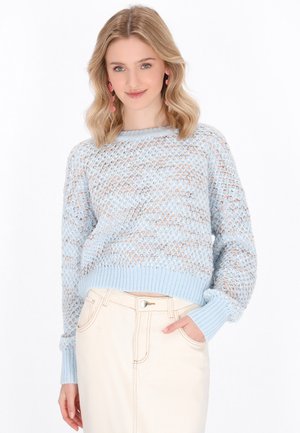 Maglione lavorato a maglia blu chiaro con una trama aperta testurizzata, polsini e orlo a coste. Abbinato a una gonna a vita alta color crema.