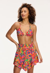 Triangulum formájú felsővel és fodros szoknyával rendelkező bikini. Élénk, színes virágmintázat pink, zöld és narancssárga színekkel. Rugalmas, könnyű anyagból készült.