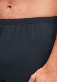 Donker marineblauwe shorts met een elastische tailleband, gemaakt van zachte, lichte stof. Heeft een eenvoudig ontwerp zonder zichtbare patronen of hardware.