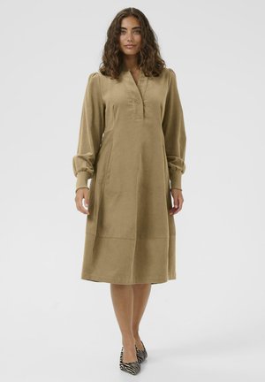 Khaki-langärmliges Kleid mit Kragen und Knopfdetail; entspannte Passform, weicher Textur und Nahtakzente; kombiniert mit gestreiften Pumps.