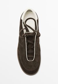 Sneaker in suede marrone con dettagli bianchi, design con lacci, collarino imbottito e superficie testurizzata. Presenta una punta arrotondata e cuciture in evidenza.