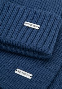 Sada námořnické pletené čepice a šály s vertikální žebrovanou texturou. Oba kusy jsou opatřeny stříbrnou kovovou značkou s vyrytým nápisem "Wittchen".