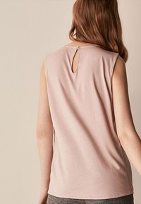 Ärmelloses Top aus weichem pinkfarbenem Stoff mit rundem Halsausschnitt und einem Schlitz auf der Rückseite, der mit einem kleinen Knopf verschlossen ist. Glatte Textur und lässige Passform.