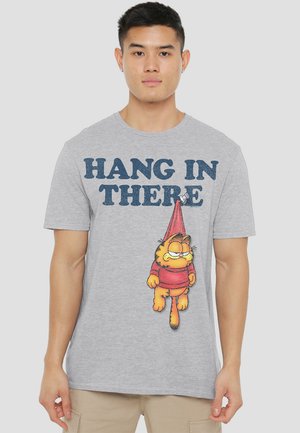 Grey cotton t-shirt featuring "HANG IN THERE" text and a cartoon of a hanging cat in a red outfit with a red hat. Short sleeves.