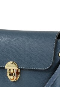 Blauwe leren handtas met een gestructureerd oppervlak, een sluiting met gouden beslag en contrasterende witte stiksels langs de randen.