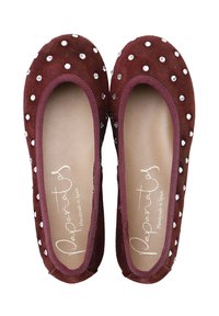 Bailarinas de ante marrón con punta redondeada, adornadas con tachuelas plateadas, y un suave forro interior con etiqueta "Hecho a mano en España".