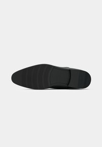 Black leather dress shoe sole with textured grip and slight heel, displayed flat against a plain white background.