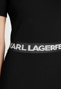 Robe en tissu côtelé noir avec manches courtes et texte blanc "KARL LAGERFELD" tricoté autour de la bande de taille.