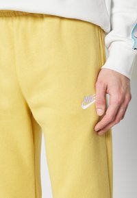 Gula joggingbyxor i mjukt tyg med elastisk midja. Har en liten vit Nike-logga broderad på framsidan.