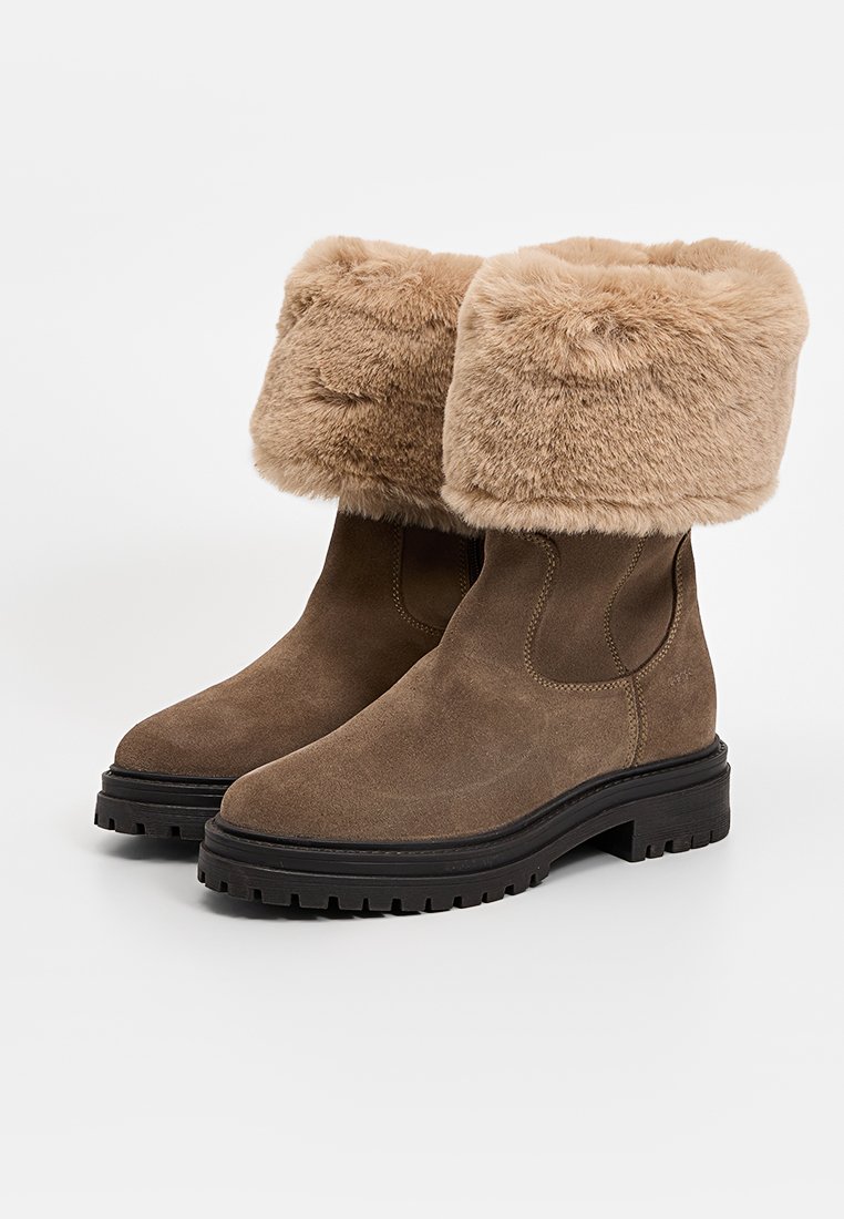 Bruine suède enkelboots met een pluizige, lichtbruine nepbontafwerking, voorzien van een stevige zwarte profielzool voor stabiliteit en grip.