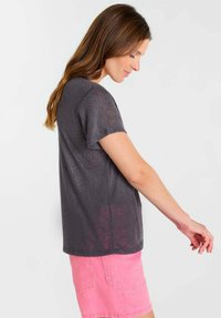 Grijs T-shirt met korte mouwen van lichtgewicht stof, met een ontspannen pasvorm en subtiele glans, gecombineerd met roze korte broek.