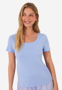 Ljusblå, kortärmad t-shirt med rund halsringning, tillverkad av mjukt tyg, med en diskret logotyp på bröstet. Slät yta.