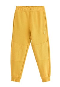 Gule joggingbukser med ribbet linning, sidelommer og teksturerede knæpaneler med prikmønster. "PLAY ALL DAY" mærke på siden.