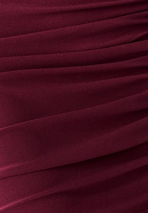 Bordová látka s mäkkou textúrou, ktorá obsahuje horizontálne záhyby vytvárajúce hĺbku a pohyb, ideálna pre formálne alebo večerné oblečenie.