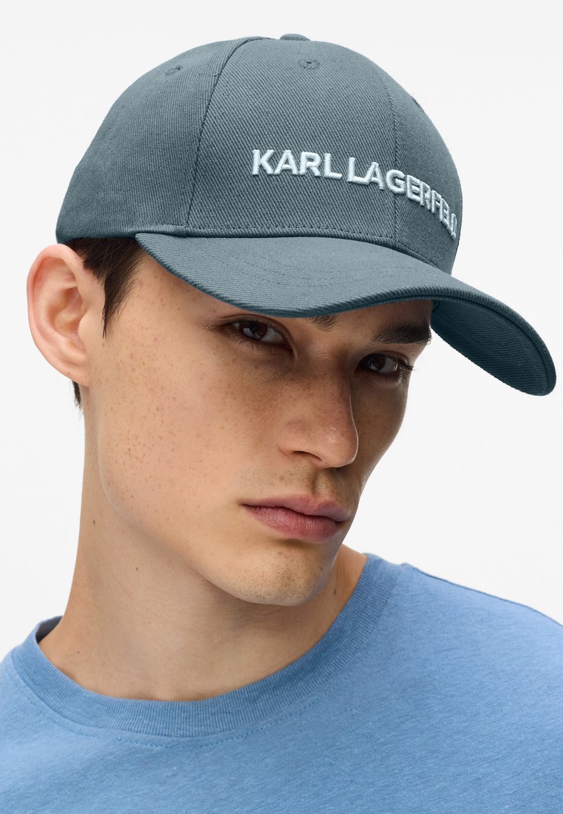 Casquette de baseball bleu sarcelle foncé avec le logo "KARL LAGERFELD" brodé. Fabriquée en tissu texturé, avec une visière incurvée et des œillets de ventilation.