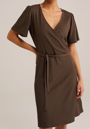 Bruine wikkeljurk met korte pofmouwen en een diepe V-hals, vervaardigd uit een gestructureerde stof en met een bijpassende ceintuur in de taille.