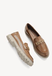Mocassins en cuir verni marron avec une surface texturée, dotés d'un détail chaîne dorée et d'une semelle épaisse couleur crème. Design à bout arrondi.