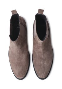 Botas Chelsea de ante marrón con una textura suave, diseño de punta afilada, Paneles laterales elásticos y tira de agarre en la parte posterior. Suela de goma negra.