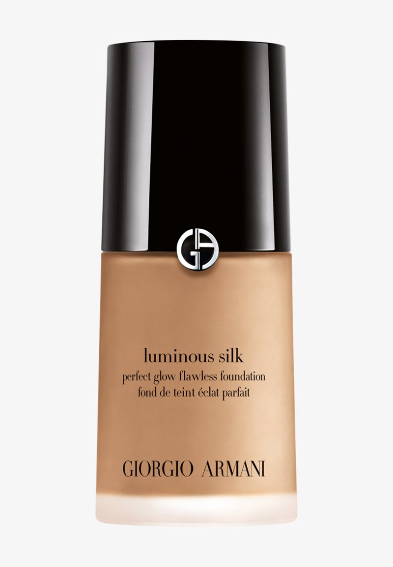 Flacon de fond de teint Giorgio Armani Luminous Silk avec bouchon noir et logo argenté, fond de teint liquide beige visible à travers le verre dépoli.