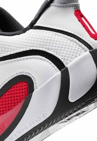 Close-up van een wit-zwarte sportschoen met rode mesh-details, een gestructureerde zool en een dempende tussenzool met het label "CUSHION 3.0".