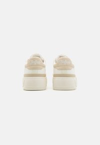 Baskets synthétiques blanches à semelle épaisse, avec des accents beiges et un arrière texturé, estampillées "Buffalo" en broderie blanche.