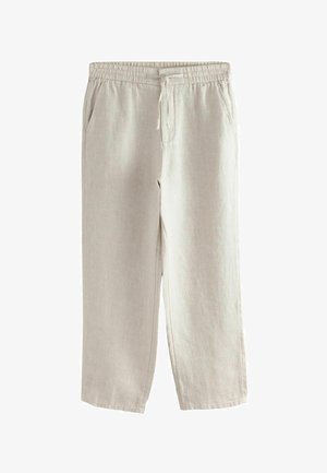 Pantalon beige texturé avec une poche plaquée à l'arrière et une taille élastique, porté par une personne à la peau foncée et une chemise blanche.