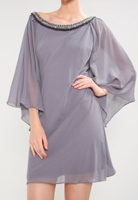 Šedé šifonové šaty s volnými rukávy a širokým, zdobeným výstřihem. Hladký materiál, délka ke kolenům a splývavý střih.