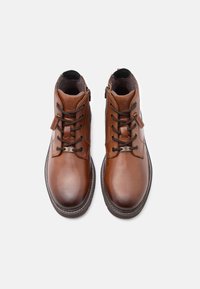 Brūni ādas potīšu zābaki ar noapaļotu purngali, saites dizainu un sānu rāvējslēdzēju. Tekstūrēta zole un nostiprinātu šuvju detaļa.