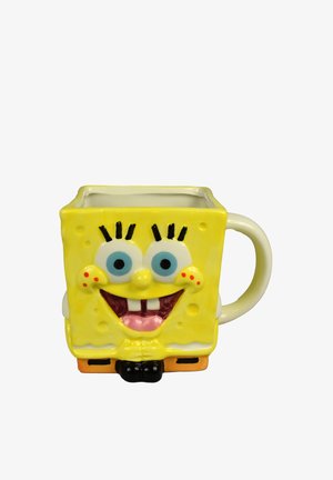 Gelber Keramikbecher in Form eines lächelnden Cartoon-Schwamm-Charakters mit großen blauen Augen, quadratischem Körper und einem Griff auf der rechten Seite.