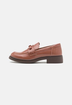 Mocassins en cuir marron à finition lisse, bout arrondi, bride décorative et petit talon marron foncé. Design simple sans motifs visibles.