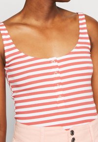 Débardeur rayé en corail et blanc, avec un décolleté en forme de U, des bretelles larges et un détail de boutons à l'avant.
