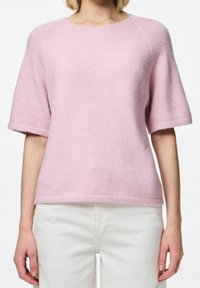 Světle růžový krátký rukáv pletený svetr s kulatým výstřihem a žebrovanými okraji, vyrobený z měkkého, texturovaného materiálu. Nosit s bílými kalhotami.