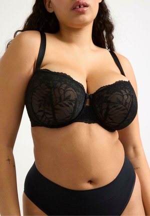 Bra balconette in pizzo nero con motivi floreali, supporto con stecche e spalline in satin regolabili. Abbinato a perizoma nero a vita alta.