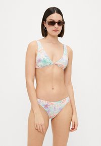 Costum de baie floral, cu un paletă de culori pastelate moi. Bustiera are un decolteu în V și bretele late; partea de jos este cu talie joasă, având motive florale asemănătoare.