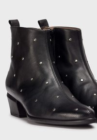 Black leather ankle boots with a pointed toe and a low block heel, adorned with silver studs and a side zipper for closure.